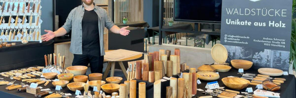Andreas Schnurrer von Waldstücke hinter seinen ganzen Unikaten aus Holz.